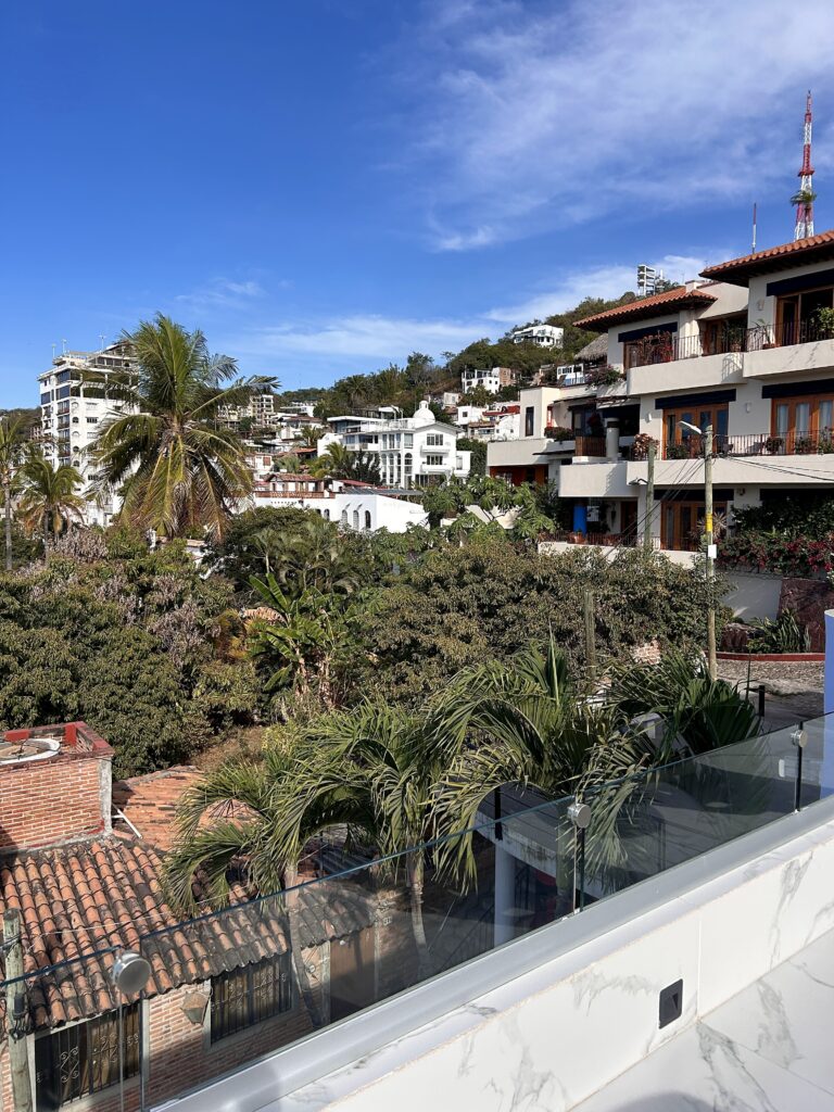 A rooftop view of green trees and hillside houses in Old Town Vallarta